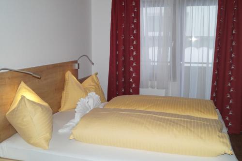 a bedroom with a bed with yellow sheets and red curtains at Sieglhub Chalets - Appartements - Hotel in Flachau