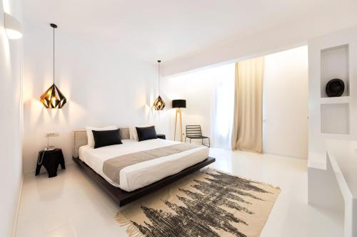 a white bedroom with a bed and a rug at Paros Agnanti Hotel in Parikia