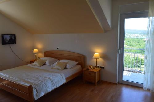 Schlafzimmer mit einem Bett und einer großen Glasschiebetür in der Unterkunft Blue Lake Luxury Rooms in Grabovica