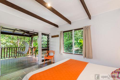 a bedroom with an orange bed and a balcony at Villa Zena in Cape Tribulation