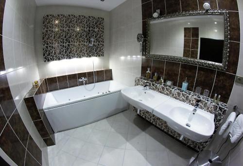 a bathroom with a tub and a sink and a mirror at Alnus Penzion in Smilno