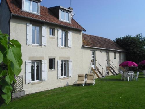 a house with chairs and umbrellas in the yard at Les 4 saisons in Graye-sur-Mer