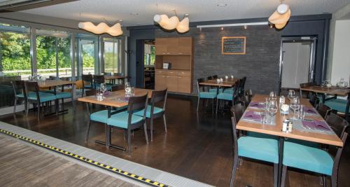 a restaurant with wooden tables and chairs and windows at Gasthof Seefeld in Hurden