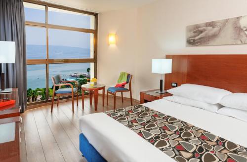 pokój hotelowy z łóżkiem i stołem z krzesłami w obiekcie Leonardo Hotel Tiberias w mieście Tyberiada