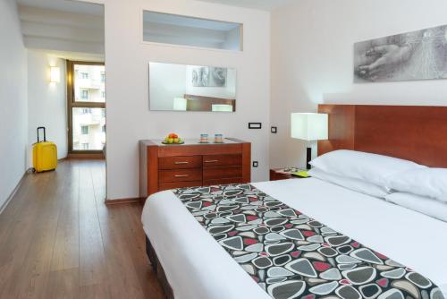 a hotel room with a large bed and a dresser at Leonardo Hotel Tiberias in Tiberias