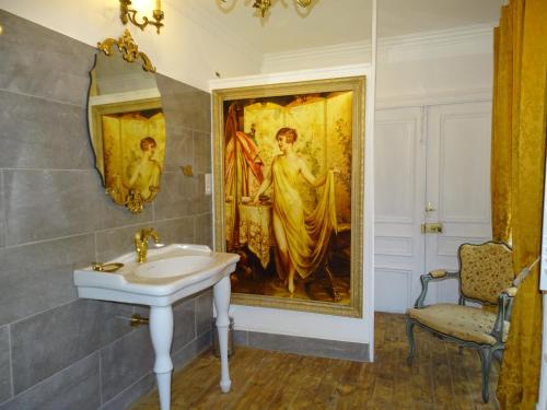 uma casa de banho com um quadro na parede e um lavatório em Château de la Forie em Saint-Étienne-sur-Usson