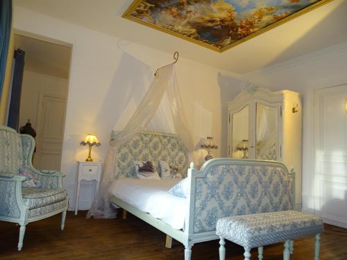 a bedroom with a bed with a canopy and two chairs at Château de la Forie in Saint-Étienne-sur-Usson