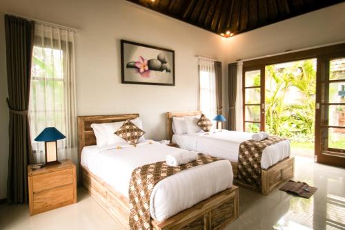 two beds in a room with windows at The Secret Spot Villas in Kusamba