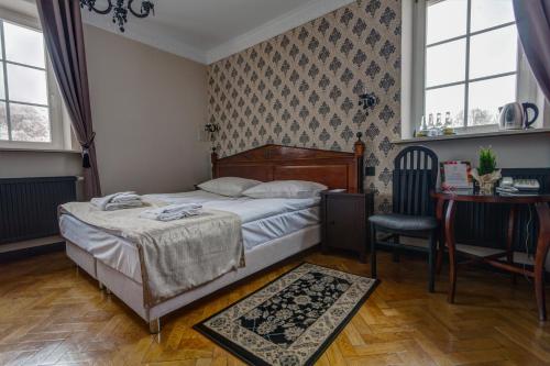 a bedroom with a bed and a table and a chair at Małopolanka & Spa in Krynica Zdrój