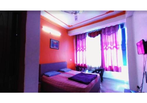 a bedroom with a bed with red walls and a window at Hotel Pratiksha in Solan