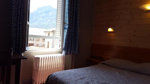 a bedroom with a bed and a large window at Hôtel Restaurant Glaizette in LʼArgentière-la-Bessée