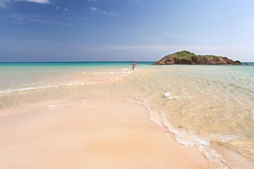 a person standing on a beach with an island in the water at La Casa di Mattia in Pula