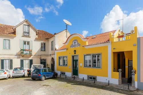 a yellow building with cars parked in a parking lot at Sintra1012 Boutique Guesthouse in Sintra