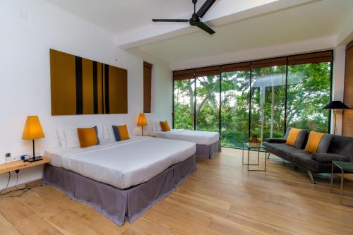 een slaapkamer met een groot bed en een bank bij Palm Paradise Cabanas & Villas Beach Resort in Tangalle