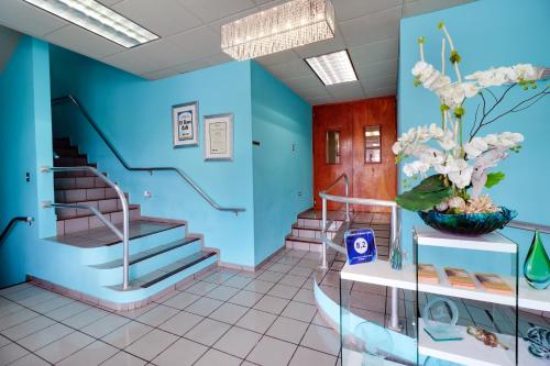 a lobby with blue walls and stairs with a vase of flowers at Parador El Buen Cafe in Hatillo