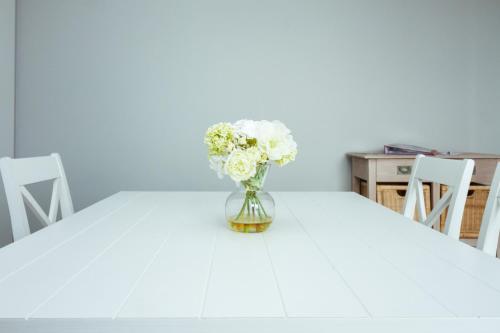 a vase of flowers sitting on a white table at Enjoy Hotel Blankenberge - Pantheon Palace By WP Hotels in Blankenberge