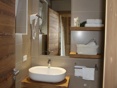 a bathroom with a sink and a mirror and towels at Fedaia Joy B&B in Canazei