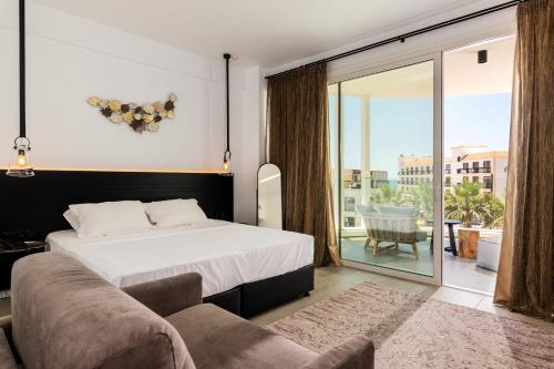 a bedroom with a bed and a couch and a balcony at Abacus Suites in Ayia Napa