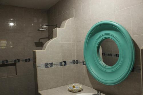 baño con espejo redondo verde y lavabo en Posada Ya´ax Ich, en Izamal