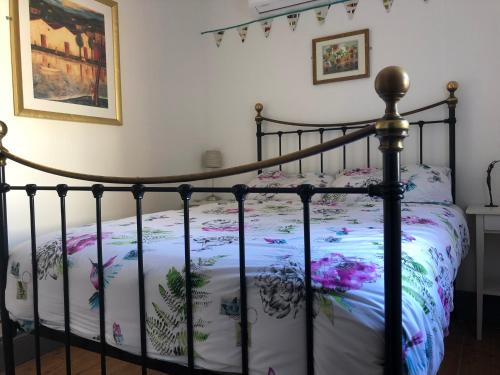 a bedroom with a black bed with a floral bedspread at Central Tavira apartment with balcony, Casa Cristina in Tavira