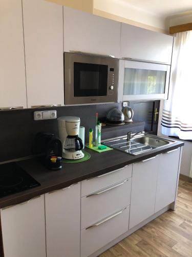 a kitchen with white cabinets and a sink and a microwave at Penzion Z&Z in Tábor