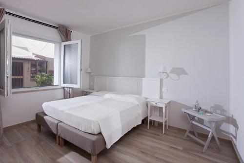 a bedroom with a bed and a desk and a window at La Casa di Mattia in Pula