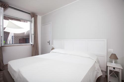 a white bedroom with a white bed and a window at La Casa di Mattia in Pula