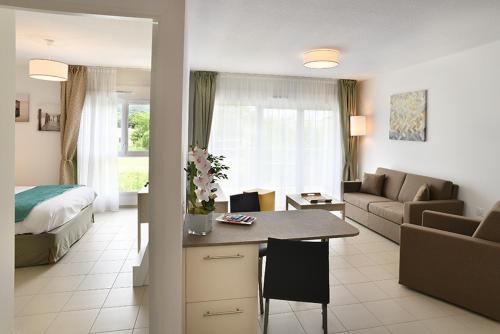 sala de estar con cama y sala de estar con mesa en Domitys Le Jardin Des Palmiers en Ajaccio