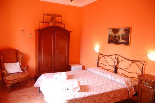 a bedroom with orange walls and a bed and a chair at Mariani Bed&Breakfast in Castellina in Chianti