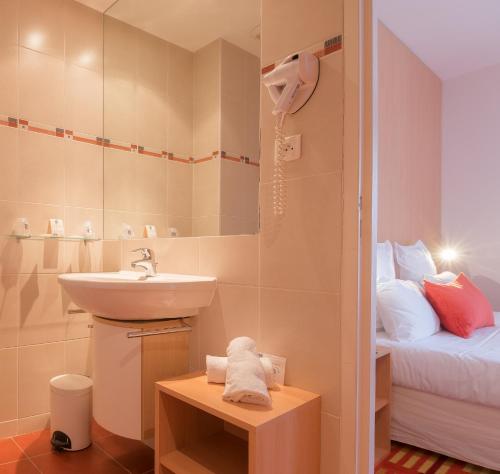 baño pequeño con lavabo y cama en Hotel Balmoral Dinard, en Dinard