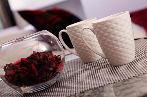two coffee cups and a glass bowl of red roses at Luxory D-Rooms in Vela Luka