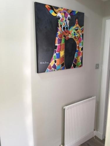 a painting of a giraffe hanging on a wall at Teviot View Holiday Let’s Hawick in Hawick