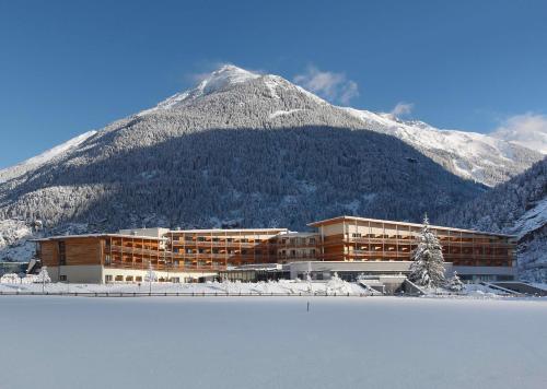 a building in front of a snow covered mountain at Aqua Dome 4 Sterne Superior Hotel & Tirol Therme Längenfeld in Längenfeld