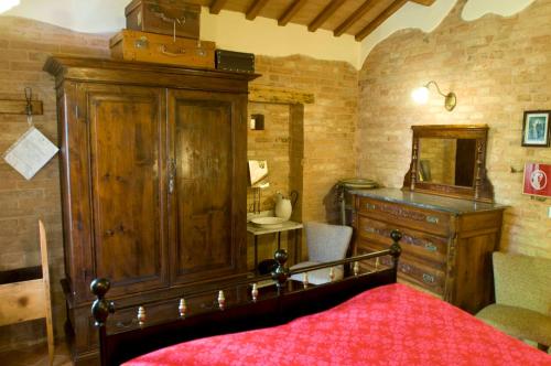 a bedroom with a large wooden cabinet and a red bed at B&B La Cappellania in Montegiorgio