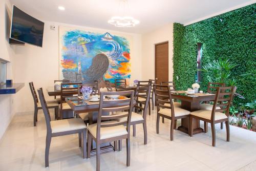 a restaurant with tables and chairs and a green wall at Hotel Posada XR in Córdoba