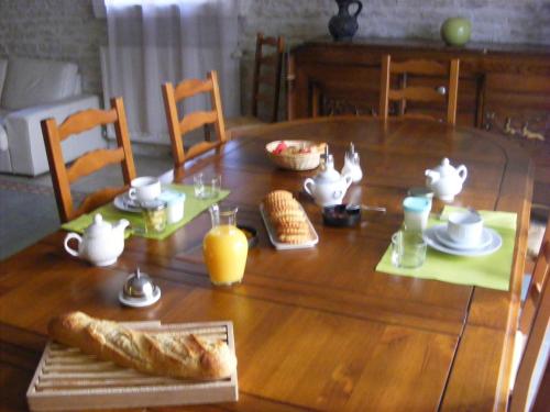 Saint-Hilaire-la-PaludにあるLe Logis de la Venise Verteの木製テーブル(パン、オレンジジュースの朝食付)