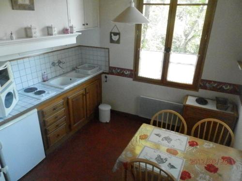 une cuisine avec un évier et une table avec des chaises dans l'établissement Les Lavandes, à Gréoux-les-Bains