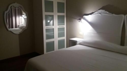 Schlafzimmer mit einem weißen Bett und einem Spiegel in der Unterkunft Hotel Chancelas in Chancelas