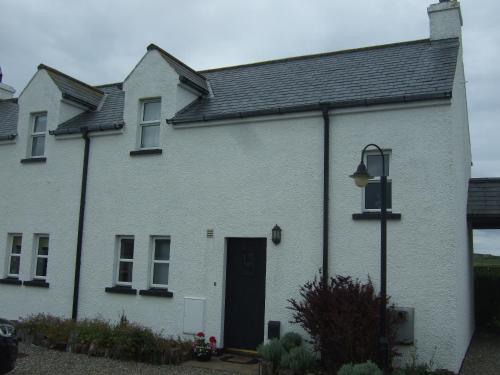 a white brick house with a black door at Aird Cottage in Aird