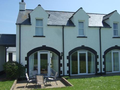a house with glass doors and chairs in the yard at Aird Cottage in Aird