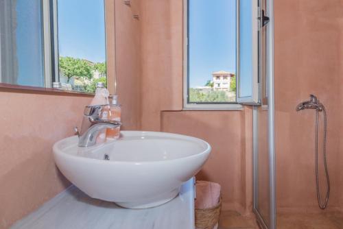 uma casa de banho com um lavatório branco e um chuveiro em ARCHONTIKO VILLAGE VOLIMES 5' minutes from the shipwreck em Volímai