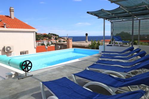 a swimming pool with blue chairs on a roof at Villa Korculaholidays in Zavalatica