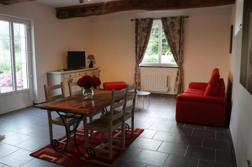 ein Wohnzimmer mit einem Tisch und einem roten Sofa in der Unterkunft Le Gite de l'Etrier in Canchy