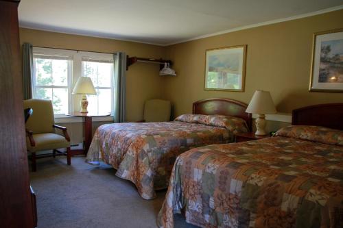 a hotel room with two beds and a window at Kennebunk Gallery Motel and Cottages in Kennebunk