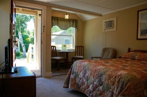 a bedroom with a bed and a door to a patio at Kennebunk Gallery Motel and Cottages in Kennebunk