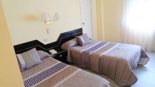a hotel room with two beds in a room at Hotel O Camiño in O Barco de Valdeorras