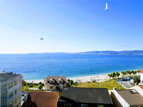 a view of a beach and the ocean with buildings at Pilar Villanueva in Bueu