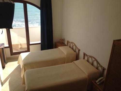 two beds in a room with a view of the ocean at Hotel Miramare Garzia in Marinella di Selinunte
