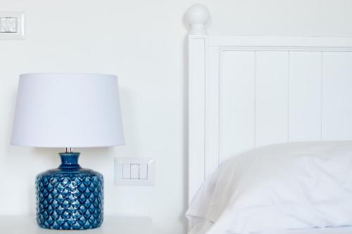 a blue vase sitting on a table next to a bed at POSEA - Polignano Sea Suites in Polignano a Mare