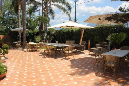an outdoor patio with tables and chairs and umbrellas at Villa Julia in Pompei